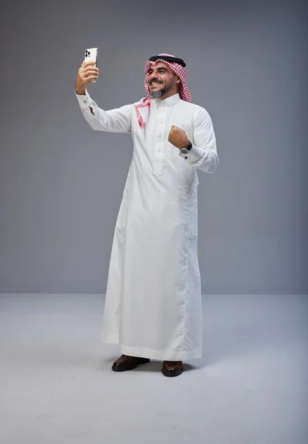 رجل سعودي بالزي التقليدي يلتقط صورة سيلفي في استوديو