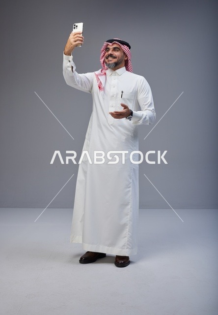 Saudi Man in Traditional Thobe Taking Selfie in Studio