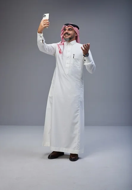 رجل سعودي بالزي التقليدي يلتقط صورة سيلفي في استوديو