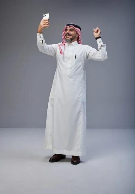 رجل سعودي بالزي التقليدي يلتقط صورة سيلفي بالجوال