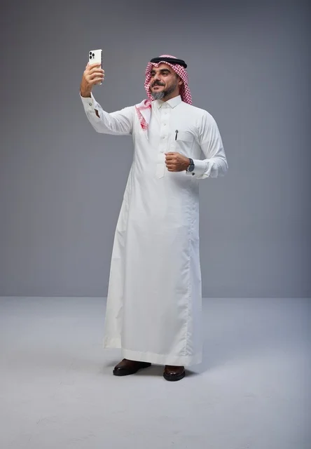 رجل سعودي بالزي التقليدي يلتقط سيلفي في استوديو
