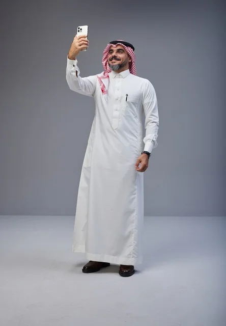 رجل سعودي بالزي التقليدي يلتقط صورة سيلفي في الاستوديو