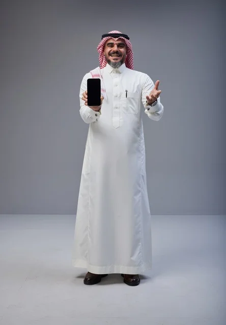 رجل سعودي بالزي التقليدي يحمل هاتف ذكي بشاشة فارغة
