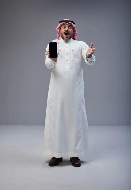 Saudi Man in Traditional Thobe Holding Smartphone in Studio