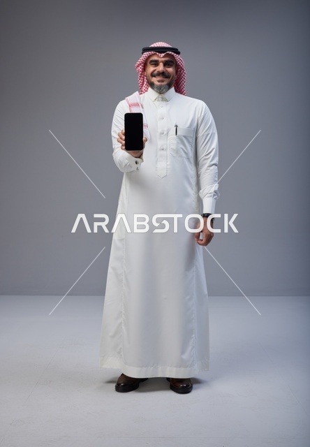 Saudi Man in Traditional Thobe Holding Smartphone Screen
