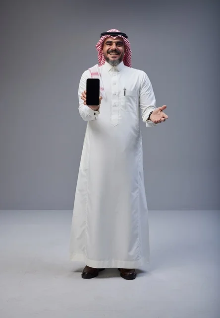 رجل سعودي بالزي التقليدي يحمل هاتف بشاشة فارغة