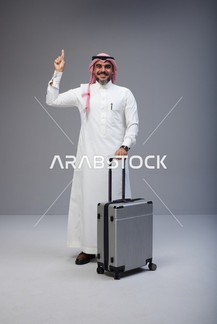 رجل سعودي بالزي التقليدي مع حقيبة سفر يشير للأعلى