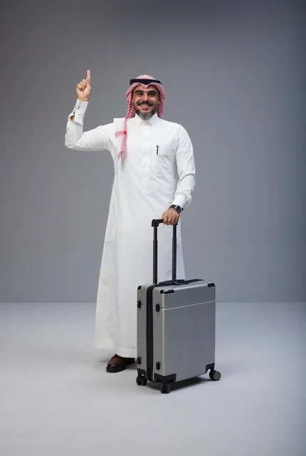 رجل سعودي بالزي التقليدي مع حقيبة سفر يشير للأعلى