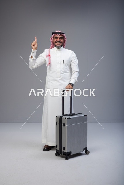 رجل سعودي بالزي التقليدي مع حقيبة سفر في الاستوديو