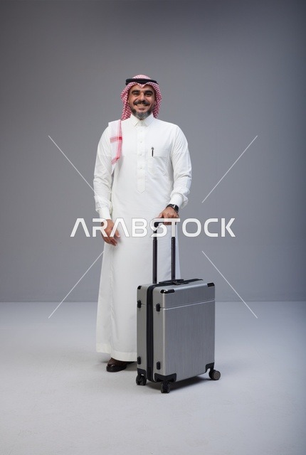 رجل سعودي بالزي التقليدي مع حقيبة سفر في الاستوديو