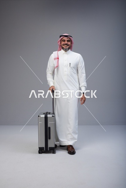 رجل سعودي بالزي التقليدي مع حقيبة سفر في الاستوديو