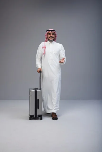 رجل سعودي بالزي التقليدي يمشي مع حقيبة سفر في استوديو