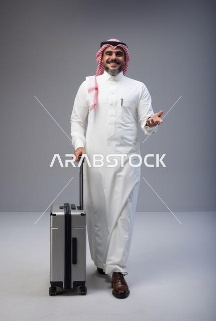 رجل سعودي بالزي التقليدي يمشي مع حقيبة سفر