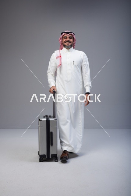 رجل سعودي بالزي التقليدي يمشي مع حقيبة سفر