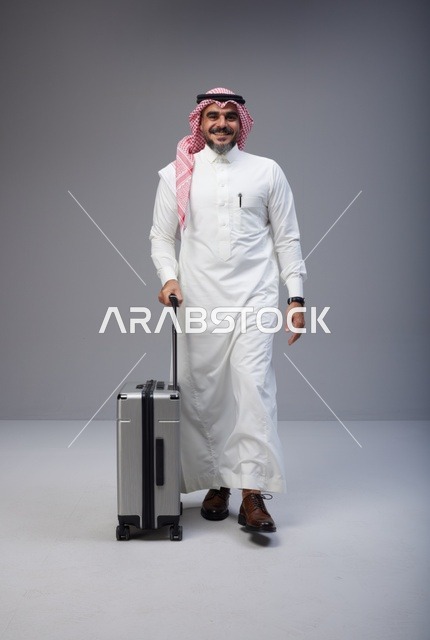 رجل سعودي بالزي التقليدي يمشي مع حقيبة سفر