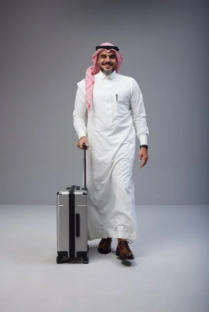 رجل سعودي بالزي التقليدي يمشي مع حقيبة سفر