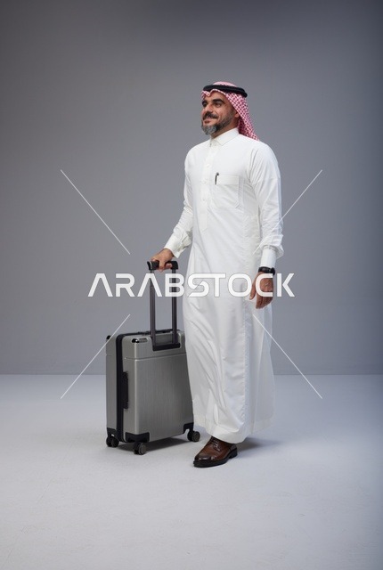 رجل سعودي بالزي التقليدي يمشي مع حقيبة سفر