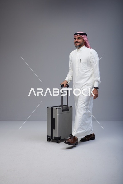 Saudi Man Walking with Travel Suitcase in Studio