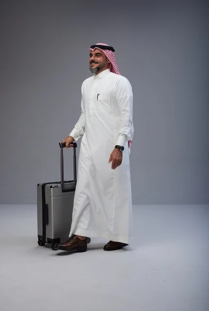 Saudi Man in Traditional Thobe Walking with Travel Suitcase