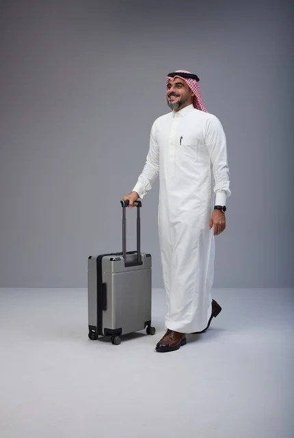رجل سعودي بالزي التقليدي يمشي مع حقيبة سفر