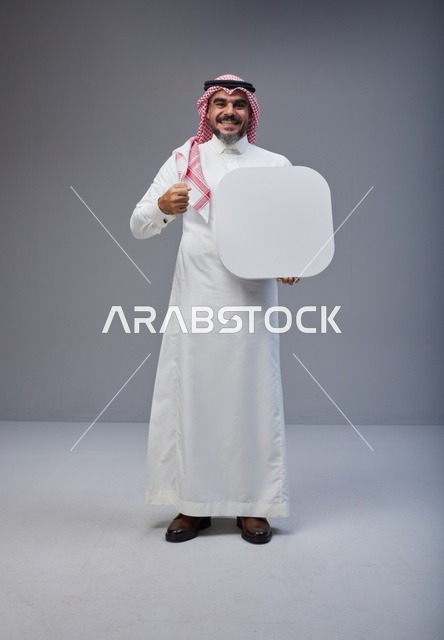 رجل سعودي يحمل لوحة بيضاء فارغة في الاستوديو