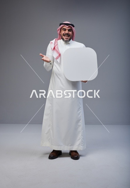 رجل سعودي يرتدي الزي التقليدي يحمل لوحة بيضاء فارغة
