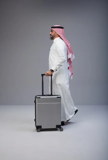 رجل سعودي بالزي التقليدي يمشي مع حقيبة سفر
