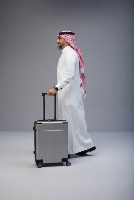 رجل سعودي بالزي التقليدي يمشي مع حقيبة سفر