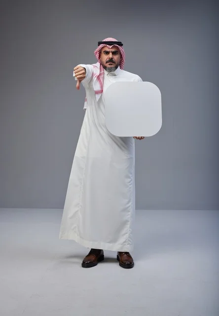 رجل سعودي يشير بعدم الإعجاب مع لوحة فارغة بيضاء