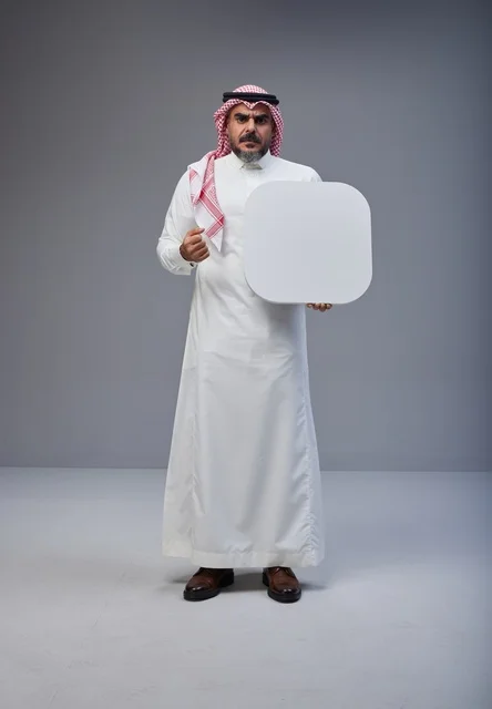رجل سعودي يحمل لوحة بيضاء فارغة في الاستوديو