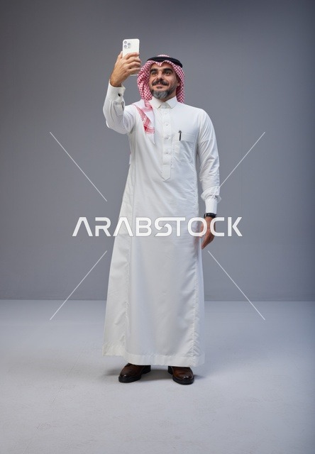 رجل سعودي بالزي التقليدي يلتقط صورة سيلفي