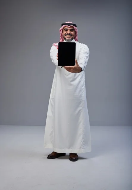 رجل سعودي يحمل جهاز لوحي بشاشة فارغة في الاستوديو