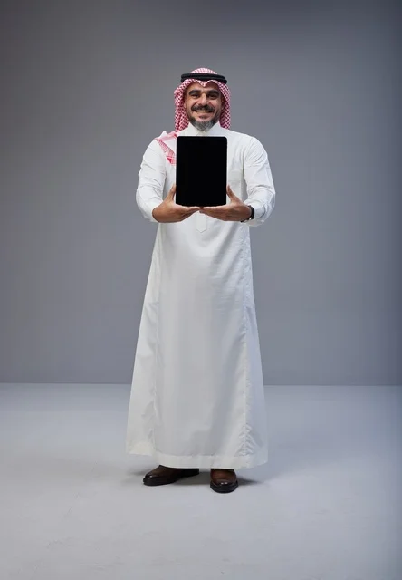 رجل سعودي يحمل جهاز لوحي بشاشة فارغة في الاستوديو