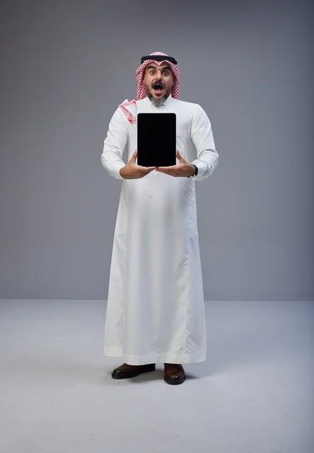 رجل سعودي مصدوم يحمل جهاز لوحي بشاشة فارغة