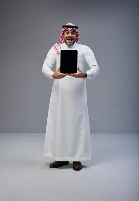 رجل سعودي يحمل جهاز لوحي بشاشة فارغة في الاستوديو