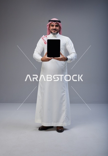 رجل سعودي يحمل جهاز لوحي بشاشة فارغة