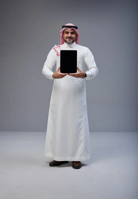 رجل سعودي يحمل جهاز لوحي بشاشة فارغة