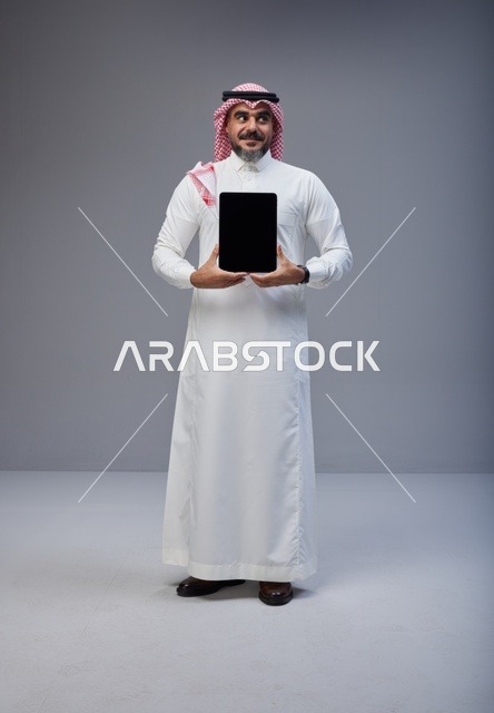 رجل سعودي يحمل جهاز لوحي بشاشة فارغة
