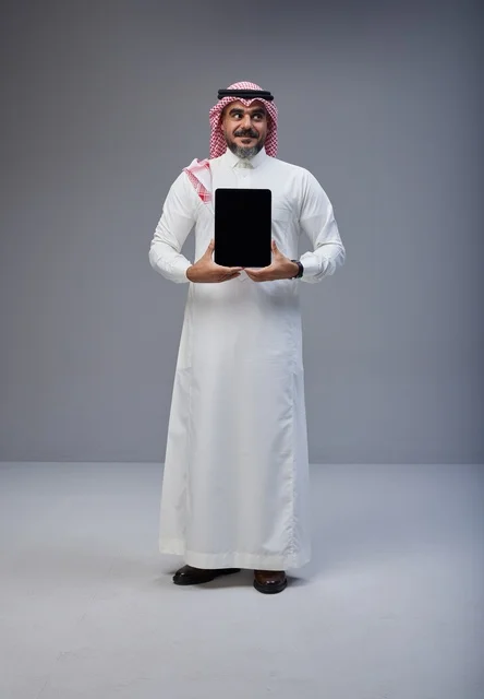 رجل سعودي يحمل جهاز لوحي بشاشة فارغة