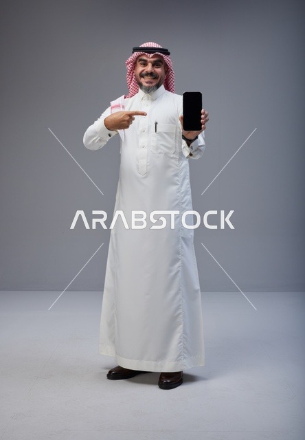 Saudi Man in Traditional Thobe Pointing at Smartphone