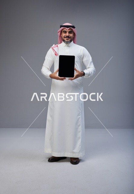 رجل سعودي يحمل جهاز لوحي بشاشة فارغة