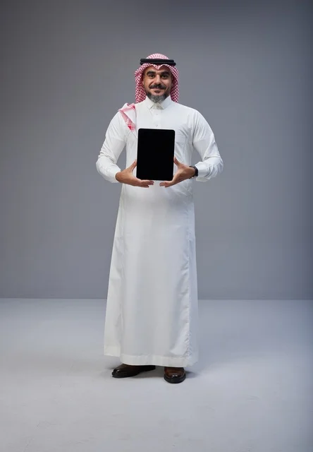 رجل سعودي يحمل جهاز لوحي بشاشة فارغة
