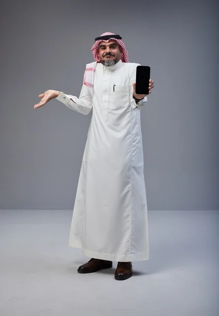 رجل سعودي بالزي التقليدي يحمل هاتف ذكي بشاشة فارغة