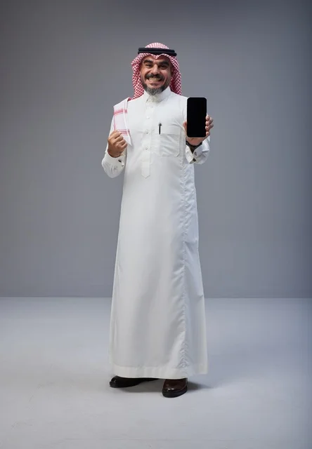 Saudi Man in Traditional Thobe Holding Blank Smartphone