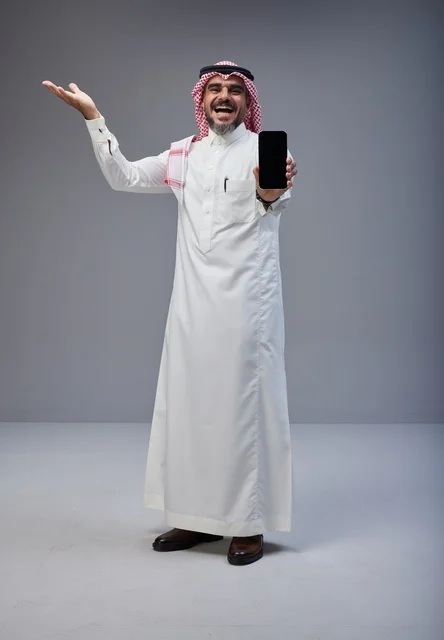 رجل سعودي بالزي التقليدي يعرض شاشة هاتف ذكي