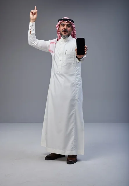 رجل سعودي بالزي التقليدي يحمل هاتف ذكي بشاشة فارغة