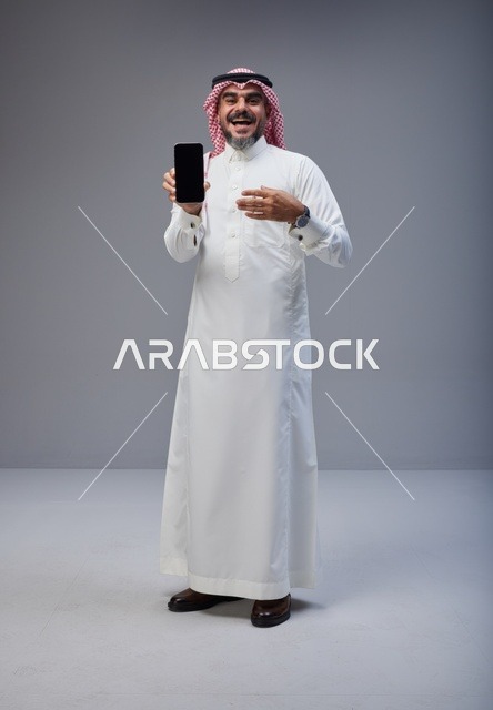 Saudi Man Holding Smartphone with Blank Screen in Studio