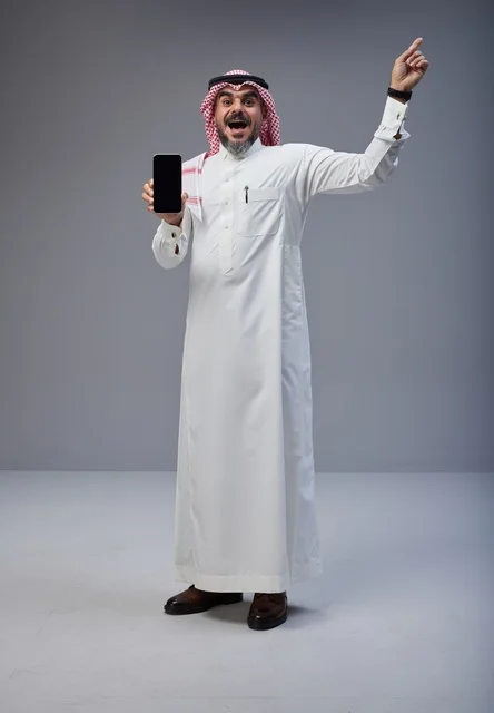 رجل سعودي بالزي التقليدي يحمل هاتف ذكي