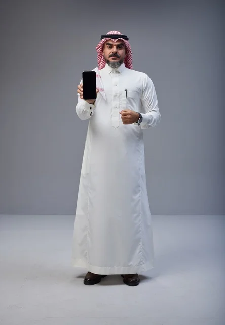Saudi Man in Thobe Holding Smartphone Screen