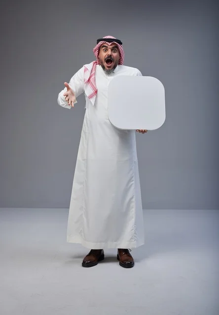 رجل سعودي مندهش يحمل لوحة بيضاء فارغة في الاستوديو
